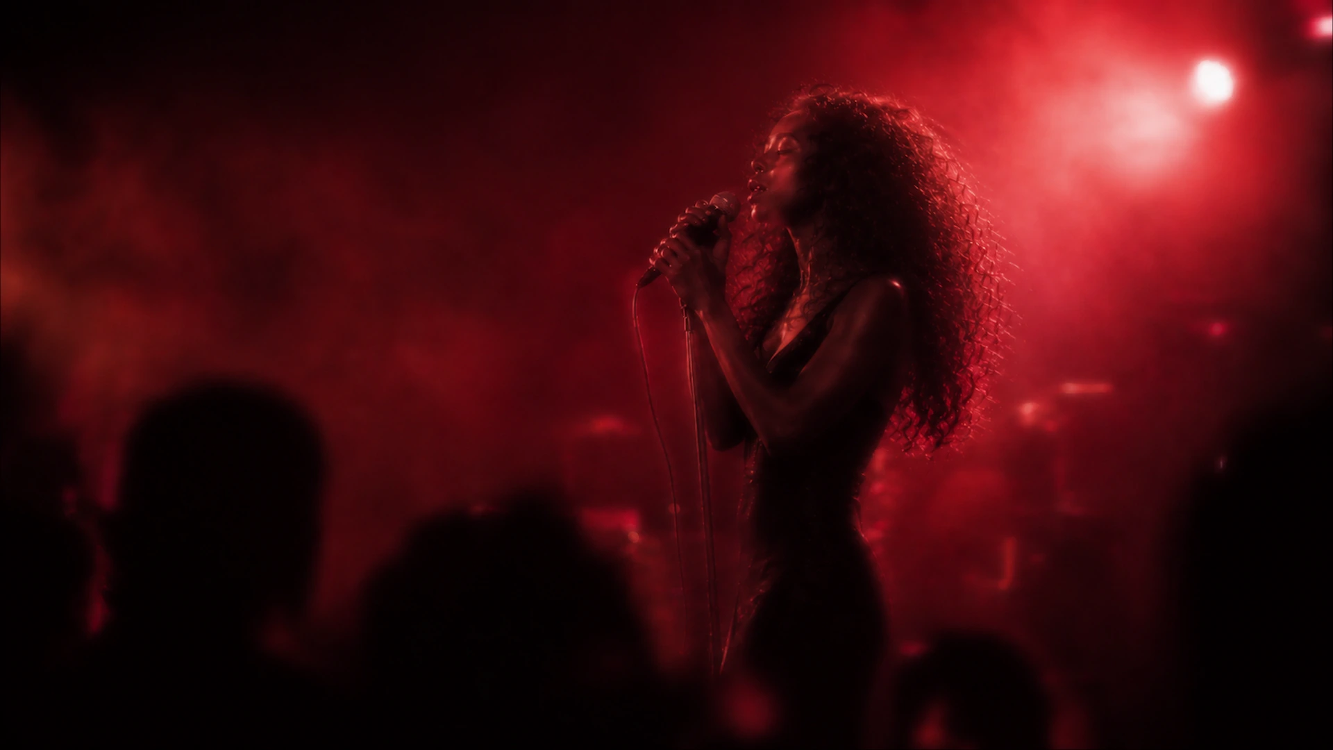 A singer performing under cinematic red stage lighting